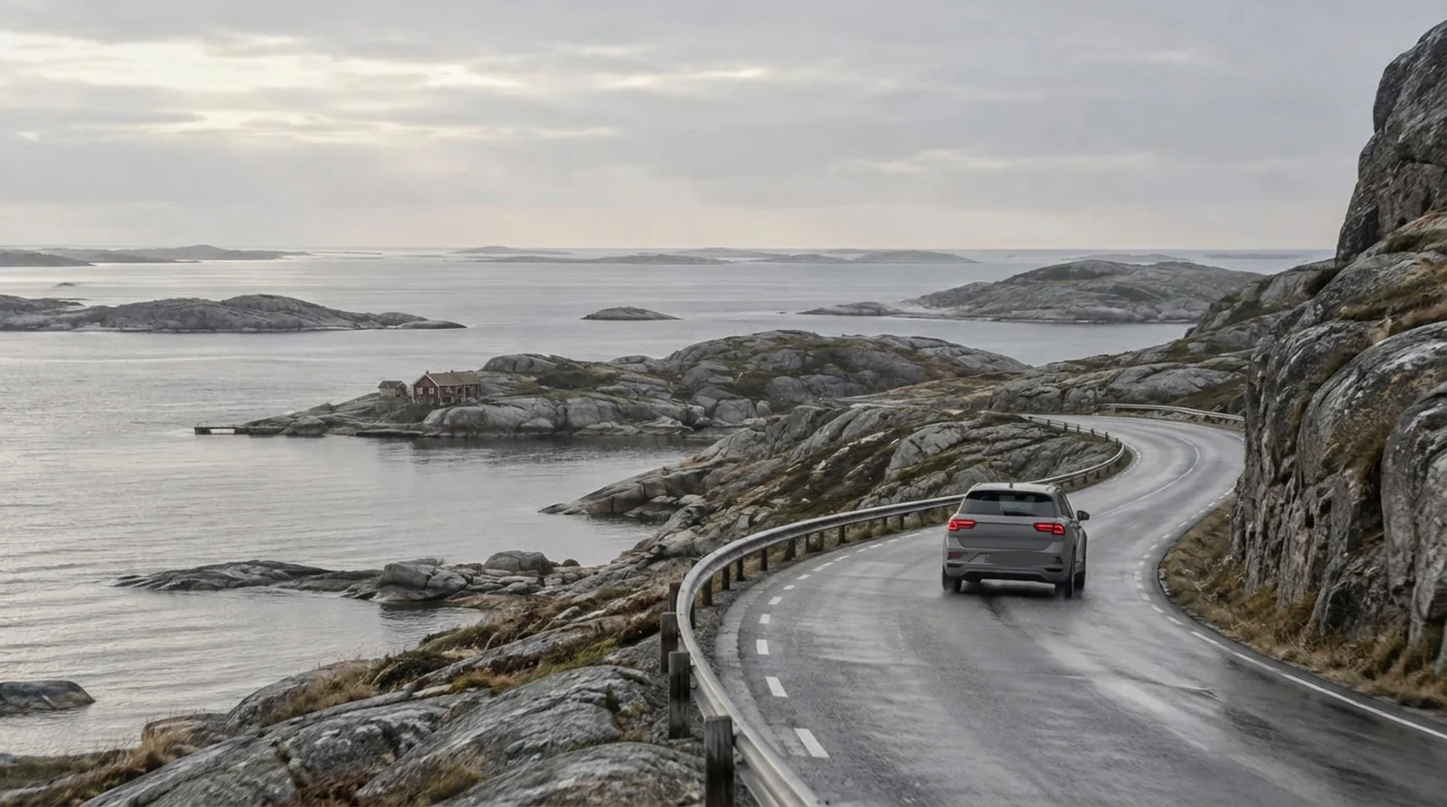 Mörk SUV på en kustväg mellan granithällar och grått hav.