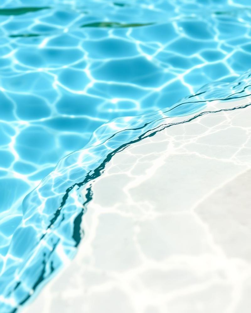 Närbild på klart turkost poolvatten mot en ljus poolkant